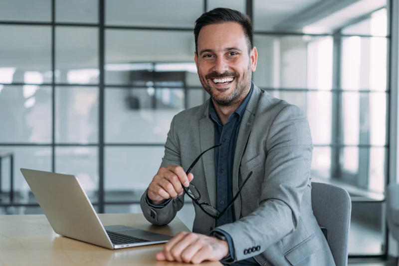 Aufnahme eines Geschäftsmannes, der an einem Schreibtisch in einem modernen Büro sitzt und an seinem Laptop mit von COMINTO maßgeschneiderter Individualsoftware arbeitet.